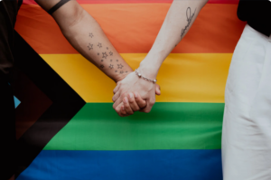 two people holding hands by a progress pride flag